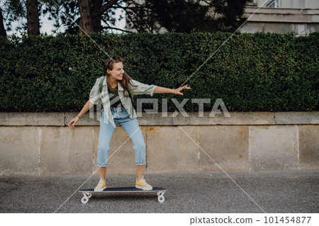 Young woman ridding skateboard in city. Youth culture and commuting concept. Young woman ridding skateboard in city. Youth culture and commuting concept. 101454877