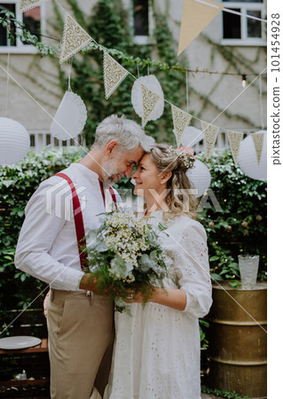 Mature bride and groom having a romantic moment at wedding reception outside in the backyard. 101454928