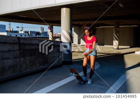 Multiracial teenage girl on skateboard in modern city during summer day. Multiracial teenage girl on skateboard in modern city during summer day. 101454995