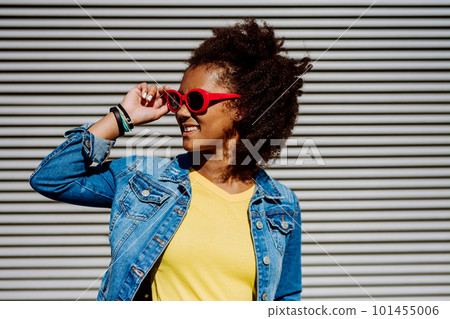 Portrait of young happy multiracial teenage girl with sunglasses and afro hairstyle, standing outdoor. Portrait of young happy multiracial teenage girl with sunglasses and afro hairstyle, standing outdoor. 101455006