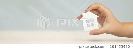 Real estate insurance. Model of a white house in hands on a gray blurred background. Insure a house or apartment, the concept of insurance services, with copy space 101455450