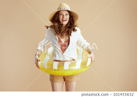smiling trendy woman in blouse and shorts jumping on beige 101455632