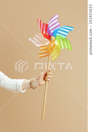 Stylish woman in blouse and shorts with windmill toy on beige 101455633