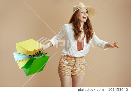 smiling 40 years old woman in blouse and shorts against beige 101455640
