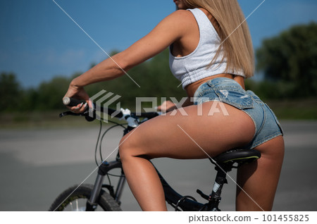 Caucasian woman in short shorts rides a bike on a hot summer day. Caucasian woman in short shorts rides a bike on a hot summer day. 101455825