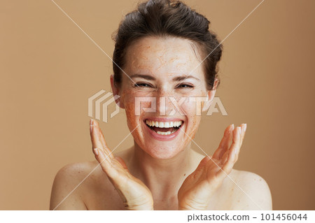 smiling modern woman with face scrub against beige background smiling modern woman with face scrub against beige background 101456044