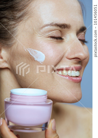 smiling modern 40 years old woman with cosmetic cream jar 101456051