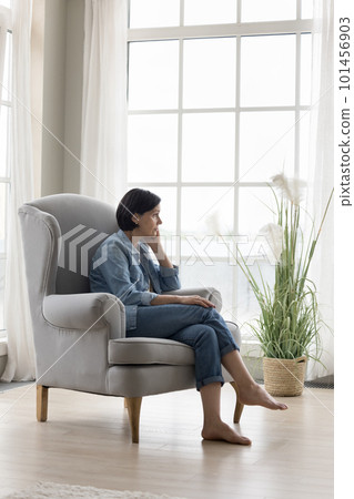 Serious thoughtful lonely mature lady sitting in armchair at home Serious thoughtful lonely mature lady sitting in armchair at home 101456903