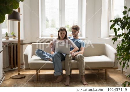 Young married couple using laptop at home, resting on couch Young married couple using laptop at home, resting on couch 101457149
