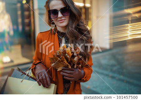 young woman in brown trench coat with shopping bags 101457500