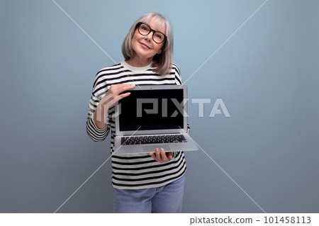 pleasant smiling middle aged 60s woman showing mockup web page on laptop on bright studio background pleasant smiling middle aged 60s woman showing mockup web page on laptop on bright studio background 101458113