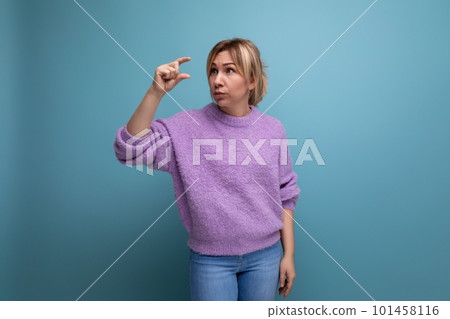 attractive blond young millennial woman in a casual look measures her hands on a bright background 101458116