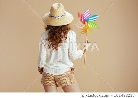 Seen from behind woman in blouse and shorts on beige 101458233