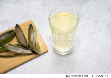 Aloe Vera Sliced Plant And Glass Of Aloe Vera Juice, Drink On Table. Horizontal plane. Food And Beverage, Antioxidant. Top view. Aloe Vera Sliced Plant And Glass Of Aloe Vera Juice, Drink On Table. Horizontal plane. Food And Beverage, Antioxidant. Top view. 101458344