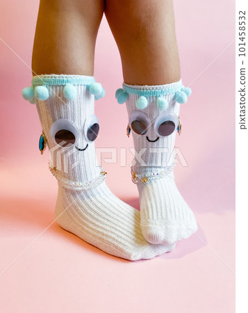 Baby socks with eyes and smile on pink background Baby socks with eyes and smile on pink background 101458532