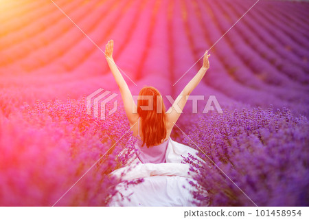 A middle-aged woman sits in a lavender field and enjoys aromathe A middle-aged woman sits in a lavender field and enjoys aromathe 101458954