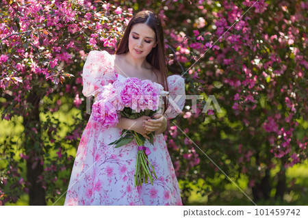A brunette girl in a dress, with a large bouquet of peonies in garden A brunette girl in a dress, with a large bouquet of peonies in garden 101459742
