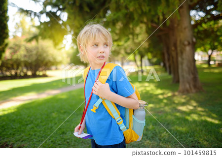 Elementary student boy with backpack, bottle of water and name badge on his neck goes to school. Happy child is waiting of school bus. 101459815