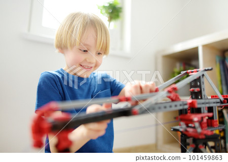 Preschooler boy playing with big construction building crane toy at home. Kids leisure activity. Entertainment for children indoors. Offline games. Preschooler boy playing with big construction building crane toy at home. Kids leisure activity. Entertainment for children indoors. Offline games. 101459863