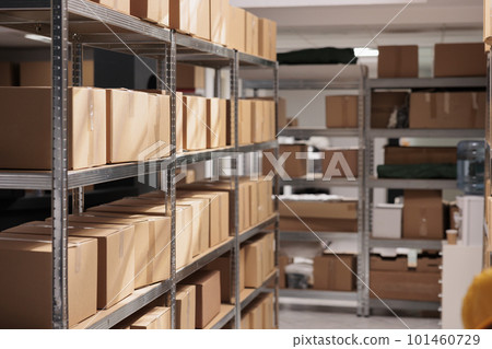 Goods packages lying on storehouse racks, waiting for transportration in empty storage. Products cardboard boxes on high shelves in shop distribution department warehouse Goods packages lying on storehouse racks, waiting for transportration in empty storage. Products cardboard boxes on high shelves in shop distribution department warehouse 101460729