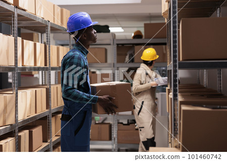 Factory shipping department employee standing with cardboard box, managing logistics and distribution. African american storehouse worker holding customer order ready for delivery Factory shipping department employee standing with cardboard box, managing logistics and distribution. African american storehouse worker holding customer order ready for delivery 101460742