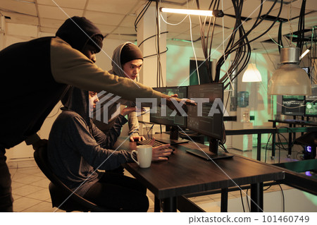 Diverse group of hackers working together to crack server, planting virus to steal personal data at night. Young criminals using monitors to hack computer network and system. Diverse group of hackers working together to crack server, planting virus to steal personal data at night. Young criminals using monitors to hack computer network and system. 101460749