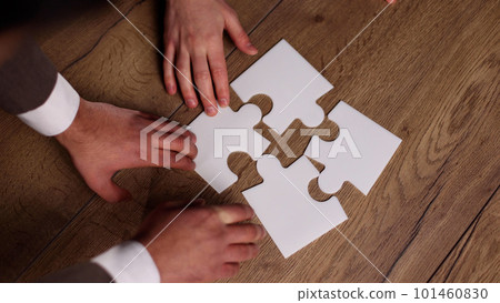 Group of business people putting together a puzzle on a table Group of business people putting together a puzzle on a table 101460830
