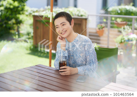 A middle-aged woman drinking iced coffee at an open cafe 101463564