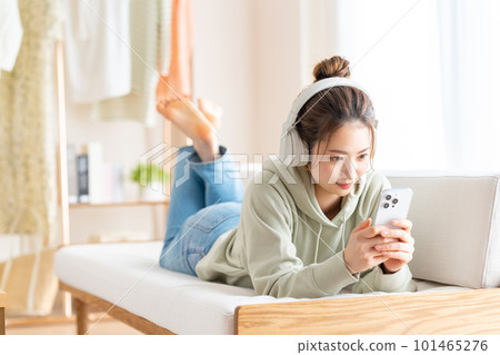 年輕女子在客廳看智慧型手機 101465276