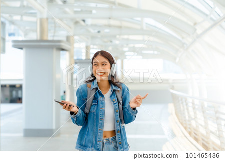 Young asian woman using headphone for listening nice music and walking in city 101465486