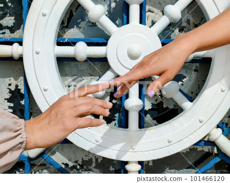 Two female hands try to touch each other with their index fingers against background of a symbolic steering wheel, concept of human relationships, partnership and unity, close-up 101466120