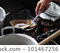 The making of a traditional Indonesian cake, originating from the Java region, named "surabi" is made from rice flour and placed in a small frying pan and topped with various toppings such as cheese.  101467256