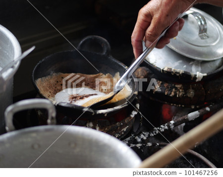 The making of a traditional Indonesian cake, originating from the Java region, named "surabi" is made from rice flour and placed in a small frying pan and topped with various toppings such as cheese.  101467256