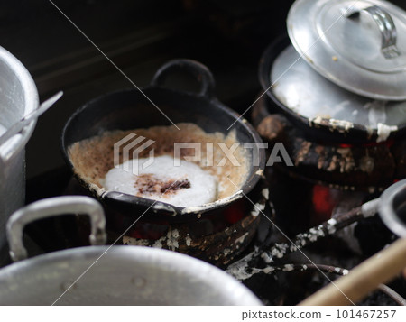 The making of a traditional Indonesian cake, originating from the Java region, named "surabi" is made from rice flour and placed in a small frying pan and topped with various toppings such as cheese. The making of a traditional Indonesian cake, originating from the Java region, named "surabi" is made from rice flour and placed in a small frying pan and topped with various toppings such as cheese. 101467257
