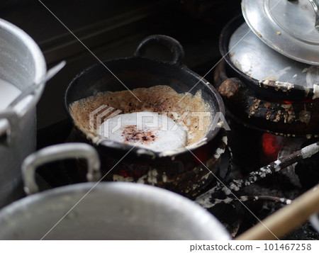 The making of a traditional Indonesian cake, originating from the Java region, named "surabi" is made from rice flour and placed in a small frying pan and topped with various toppings such as cheese.  101467258