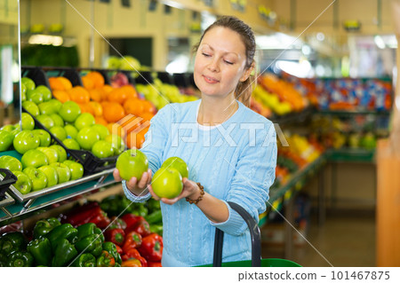 Middle-aged woman purchaser buying fresh apples in grocery store Middle-aged woman purchaser buying fresh apples in grocery store 101467875