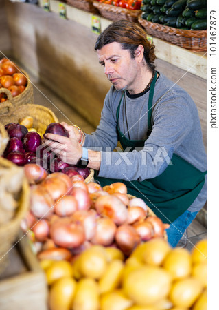 Male salesman near fruit and vegetables stalls offering to buy red onion 101467879