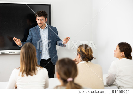 Young male professor explaining subject to classroom full of students 101468045