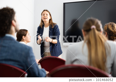 Confident female trainer talking to group of people, brainstorming, discussing ideas in auditory Confident female trainer talking to group of people, brainstorming, discussing ideas in auditory 101468052