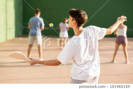 Concentrated young man paleta fronton player hitting ball with racket 101468189
