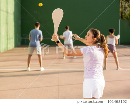 Portrait of sporty girl playing paleta fronton on outdoor court, ready to hit ball. Healthy and active lifestyle concept 101468192