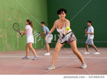 Woman playing frontenis with partners at sunny day, healthy lifestyle concept 101468193