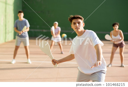 Concentrated young man paleta fronton player hitting ball with racket 101468215