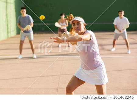 Active womans with enthusiasm playing paleta fronton group on outdoor court 101468246