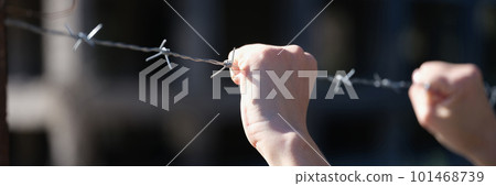 Woman hands holding metal security barbedwire fence 101468739