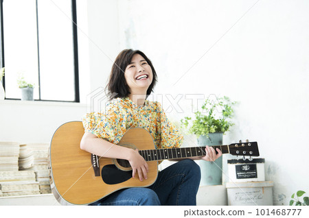 Smiling young woman playing guitar Smiling young woman playing guitar 101468777