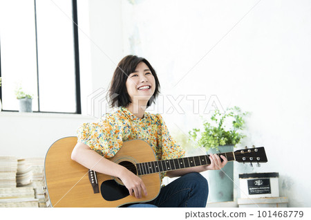 Smiling young woman playing guitar 101468779