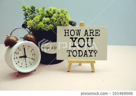 How are you today? written on paper card with artificial plant and alarm clock on blue background 101469006