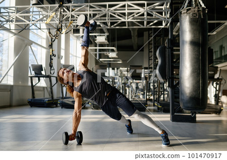 Muscular sportsman training with heavy weights dumbbells showing strong body 101470917