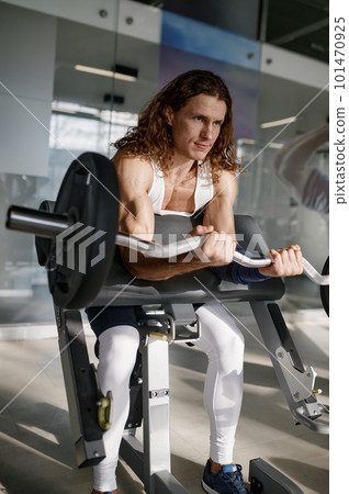 Man bodybuilder working with barbell on Scott bench at gym 101470925